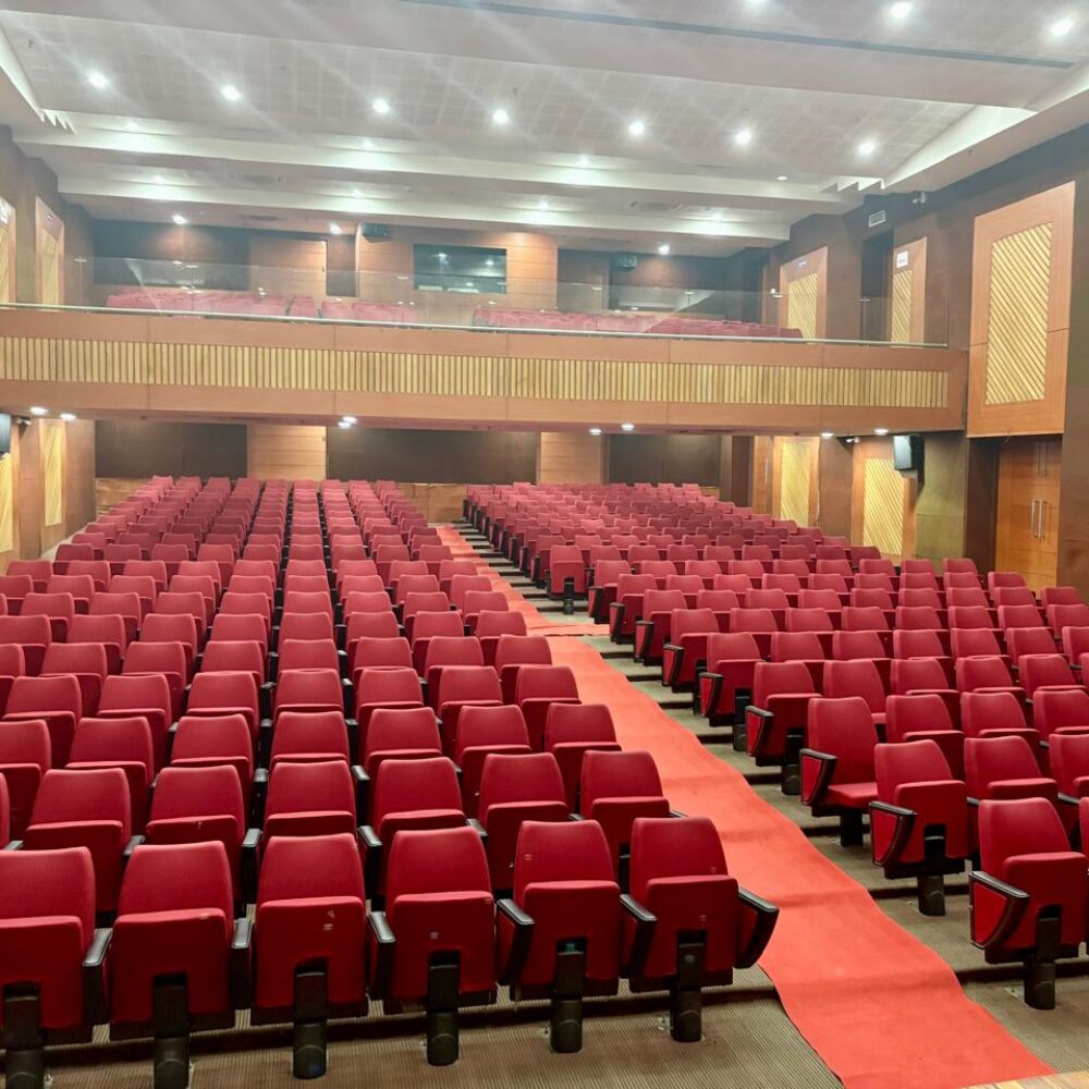 Spacious auditorium furnished with red auditorium chairs by Flexi Seating System