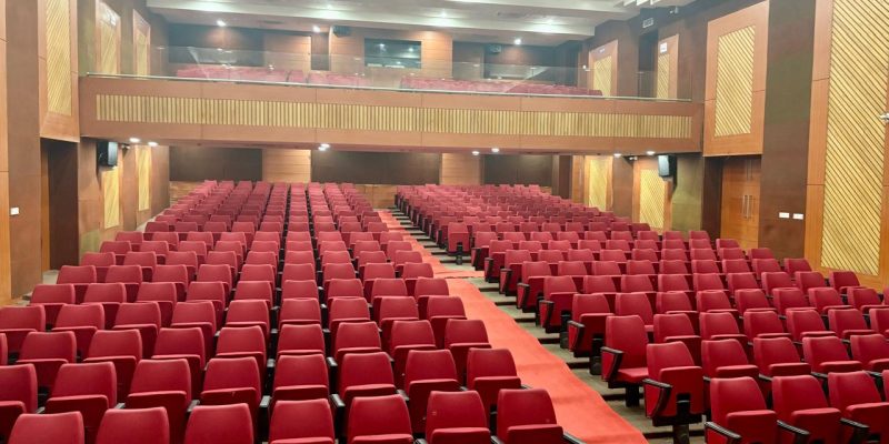 Spacious auditorium furnished with red auditorium chairs by Flexi Seating System
